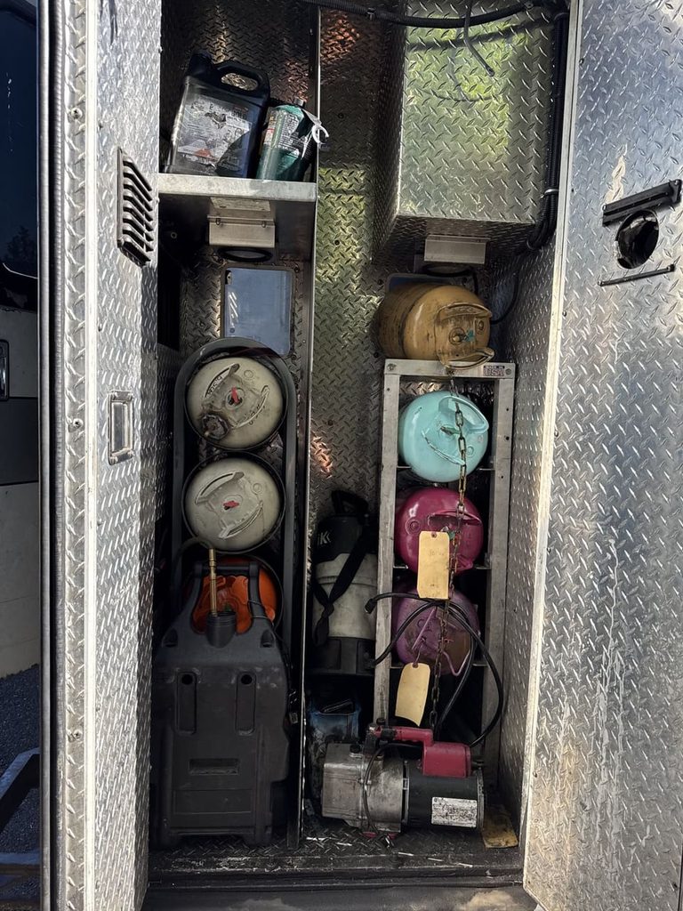 Refrigerant tanks and recovery equipment ride in a side compartment of the truck.