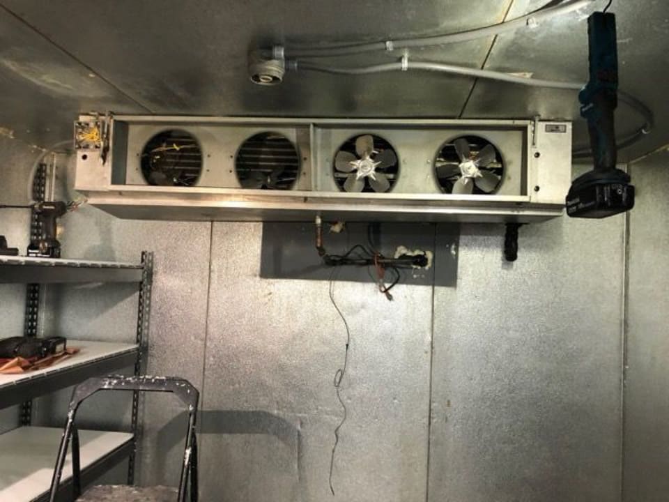 The evaporator coil and fans inside a walk-in cooler, the kind of equipment the business repairs.
